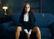 Nun in a cassock sitting spreading her legs