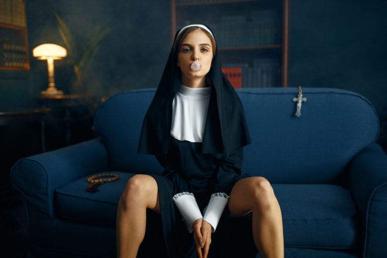 Nun in a cassock sitting spreading her legs