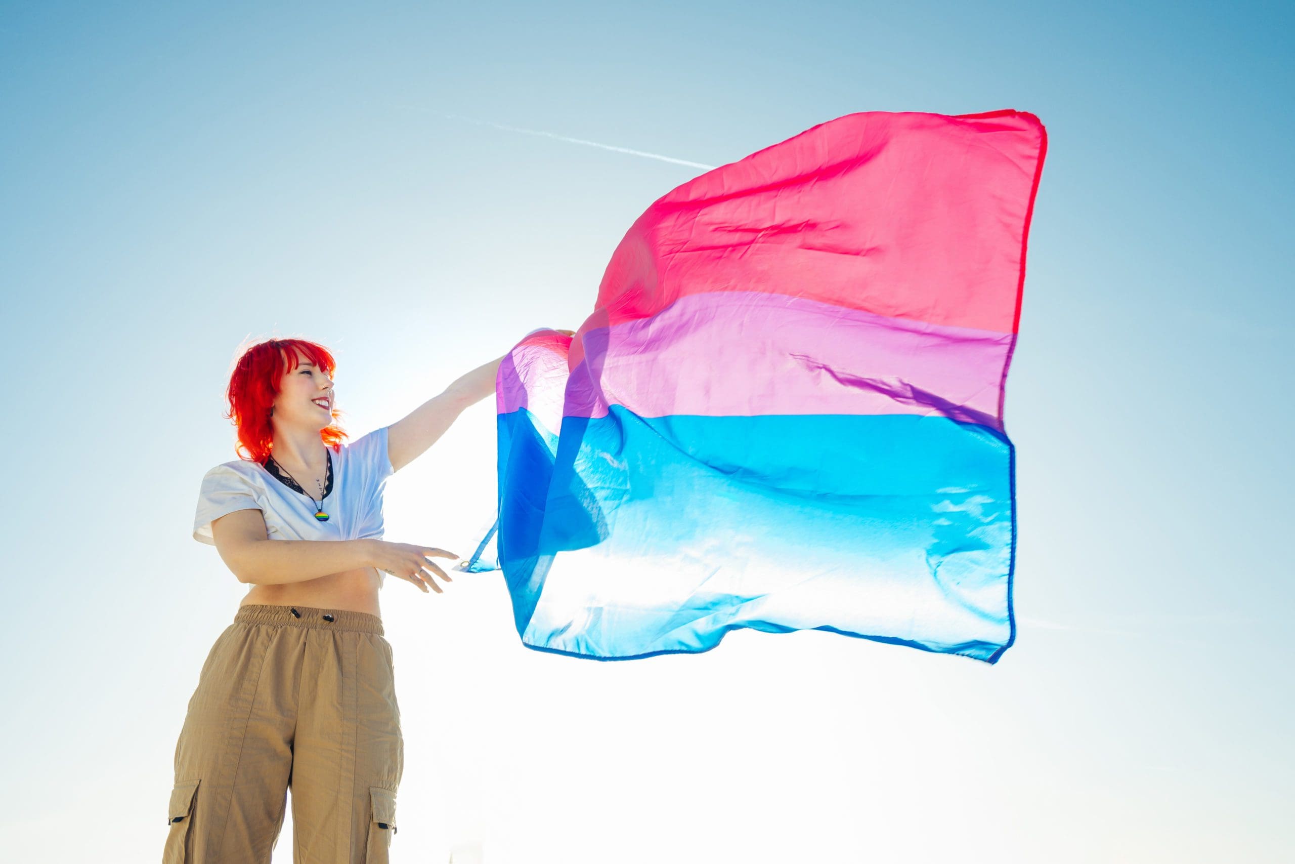 Young woman with red hair waving a colorful flag