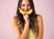 beautiful woman holding a banana in front of her mouth