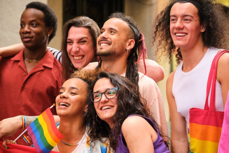 A group of people are smiling and holding rainbow flags
