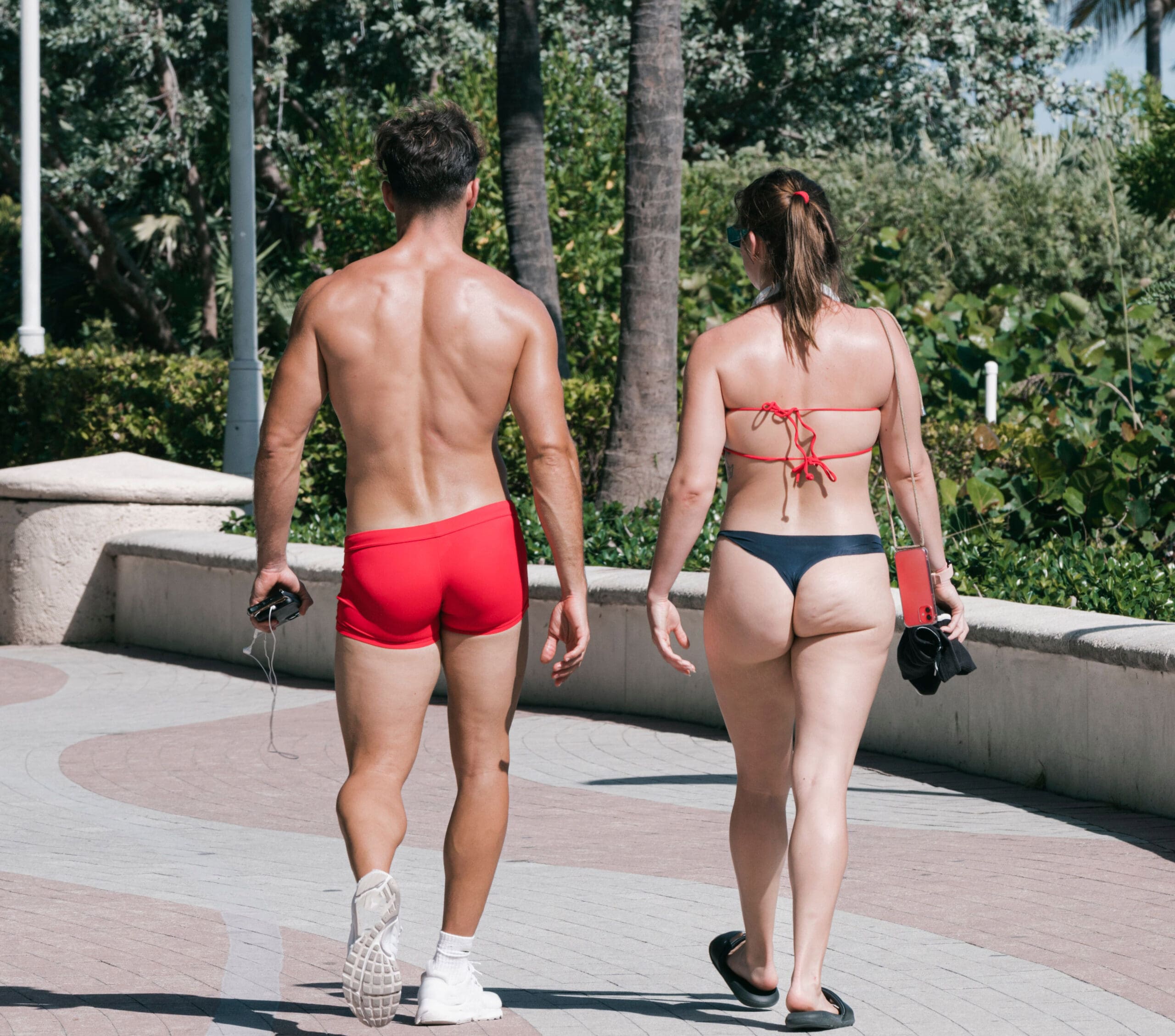 a man and woman walking in bathing suits in the park