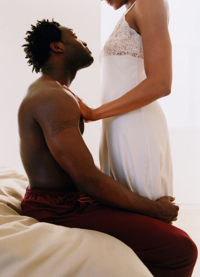 Share Your Fantasies Woman wearing a pretty white night gown standing over her man who is sitting on the side of a bed